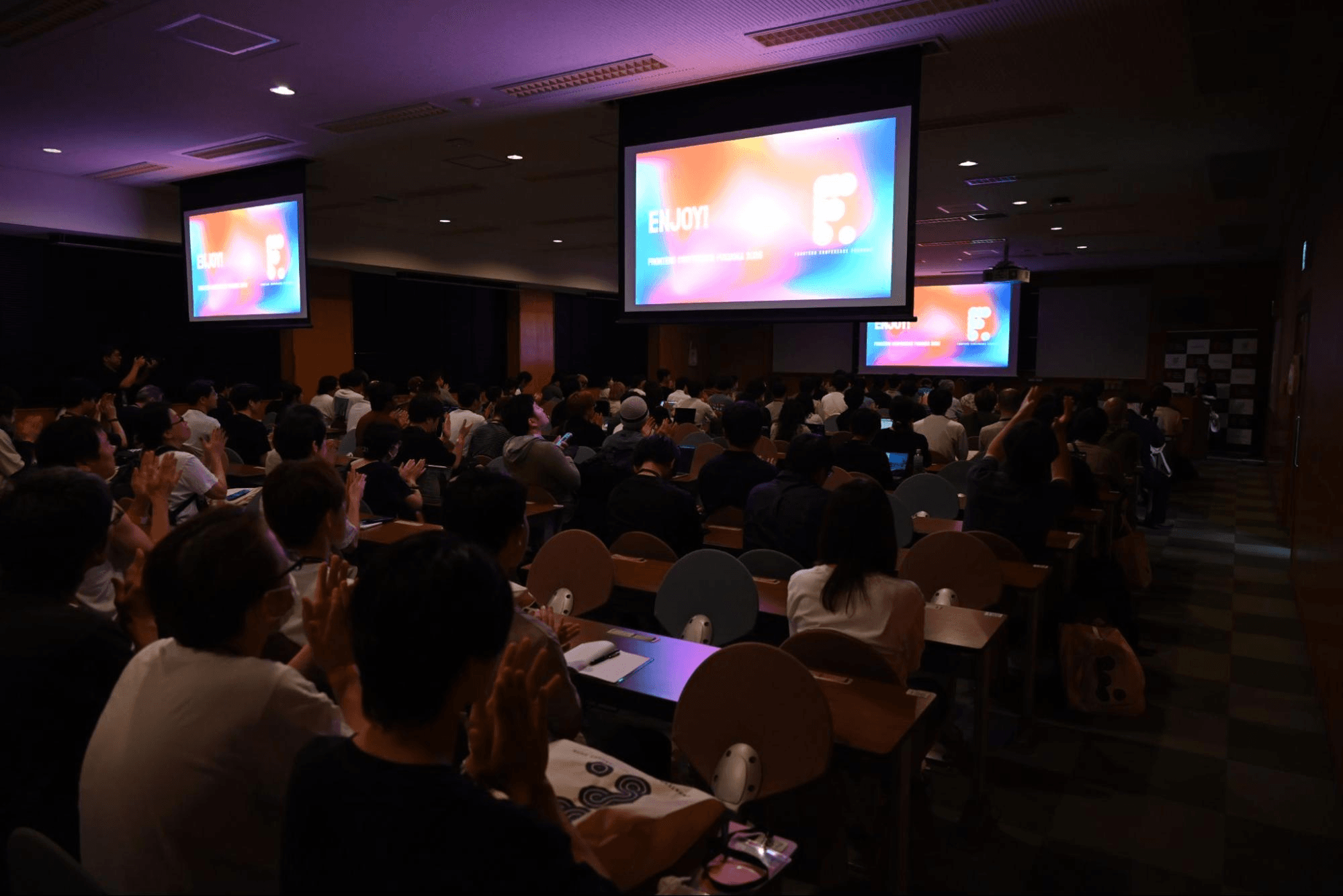 オープニングで「ENJOY!」のスライドが映り、拍手する満席の会場