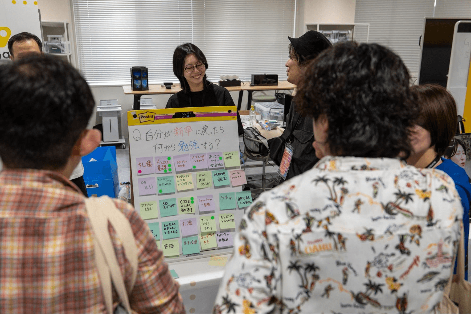 「自分が新卒に戻ったら何から勉強する?」と問いかける付箋ボードを囲み、ブースで談笑する参加者